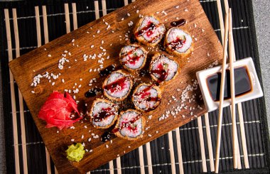 Kızarmış rulo, salatalık ve kırmızı havyar. Ahşap arka plan. Soslu beyaz bardak. Çin yemek çubukları.