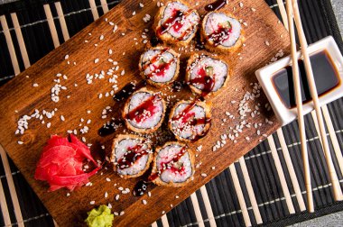 Kızarmış rulo, salatalık ve kırmızı havyar. Ahşap arka plan. Soslu beyaz bardak. Çin yemek çubukları.