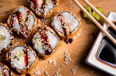 Izgara rulo, sebze, peynir ve susam tohumu. Ahşap arka plan. Soslu beyaz bardak. Çin yemek çubukları.