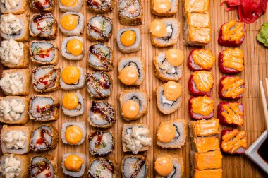 Kahverengi bir tepside fırında rulo. Menü için fotoğraf. Soslu bir fincan. Çin yemek çubukları.