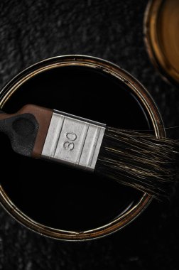 Boya fırçası açık kahverengi boya kutusunda yatıyor. Siyah arkaplan.