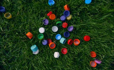 Yeşil çimenlikteki plastik şişe kapakları. Çöp toplama. Parlak nesneler       