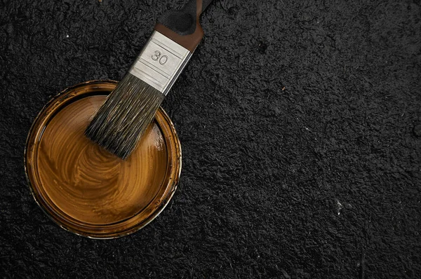 The outer brush in the brown paint. Home repair. Dark background. Creating handmade furniture. Tinting the tree.