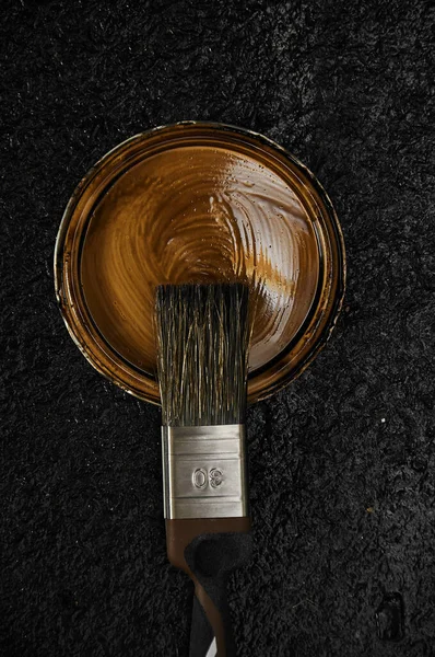 画笔躺在一罐棕色油漆的敞篷上 黑暗的背景木制波兰人 — 图库照片