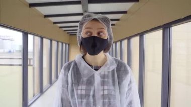 Sabahlık giymiş ve maske takmış genç bir kız etrafa bakıyor..