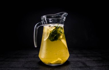 Limonlu, naneli ve buzlu doğal limonata. Siyah, izole bir arka planda, bir sürahide alkolsüz içecek. Şerbetli karbonatlı su.