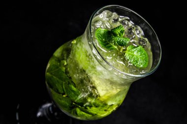Limonlu, naneli ve buzlu mojito. İzole edilmiş, siyah bir arkaplanda güzel bir kokteyl..