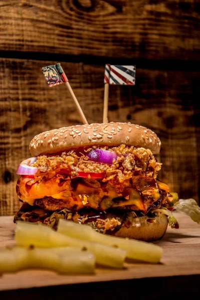 Ahşap arka planda kocaman lezzetli bir burger. Ananaslı hamburger. Sulu soğan, domates, salatalık, pirzola..