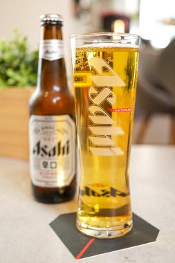 Restoran masasında bira şişesi ve cam manzarası var.