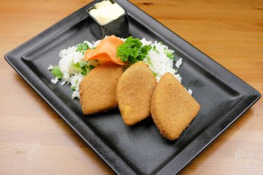 Lokantadaki ahşap masada nefis ana yemek tabağının yakın çekimi.