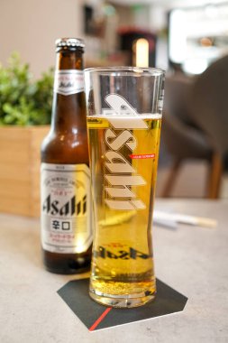 Restoran masasında bira şişesi ve cam manzarası var.