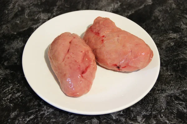 Beyaz bir tabakta soyulmuş ve işlenmiş sığır yumurtası (testisler)