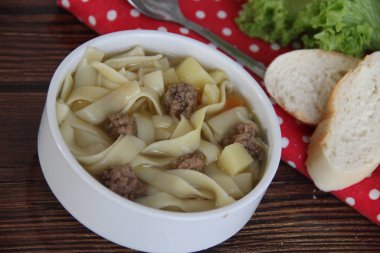 Beyaz çorba kasesinde köfteli kalın erişte çorbası.