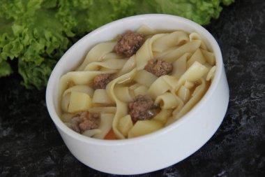 Beyaz çorba kasesinde köfteli kalın erişte çorbası.