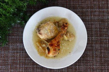 Beyaz tabakta soğan soslu fırında tavuk budu.