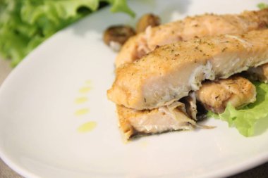 Beyaz bir tabakta kırmızı balık parçaları, marul yaprağı, yakın görüş.