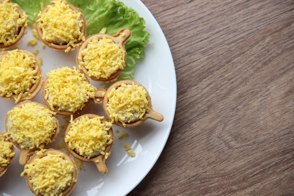 Doldurulmuş aperatif tart. Sepetler dolusu balık ciğeri, yumurta ve peynir, yumurta sarısı serpiştirilmiş. Yukarıdan görünüşü