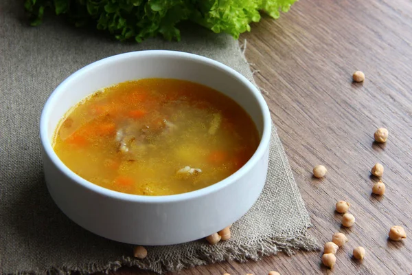 Chickpea soup in a white plate on a sackcloth, with dried chickpeas scattered nearby. Garbanzo bean soup — Stock Image Chickpea Soup White Plate Sackcloth Dried Chickpeas Scattered Nearby Garbanzo Royalty Free Stock Images