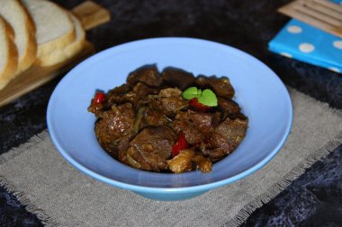 Mavi bir kasede sebzelerle pişirilmiş yan ürünler (hindi taşlığı)