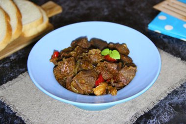 Mavi bir kasede sebzelerle pişirilmiş yan ürünler (hindi taşlığı)