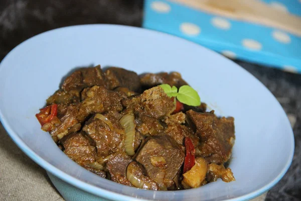 Et, mavi bir tabakta soslu sebzelerle pişirilmiş.