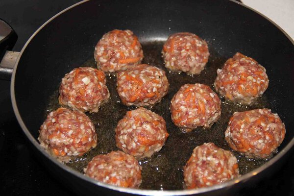 Homemade meatballs still raw are cooked in a frying pan