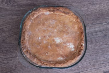 Ahşap bir arka planda pişirme kabını dolduran ev yapımı turta.