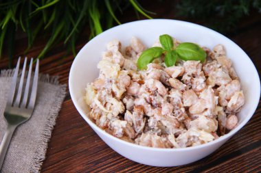 Deniz taraklı salata, fasulye ve peynir beyaz bardakta.