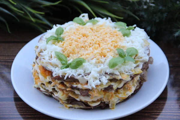 Yumurta ve otlarla süslenmiş, mayonezle batırılmış, soğan ve havuçla süslenmiş ciğer keki.