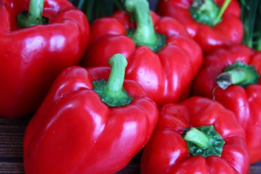 Tahta bir masada yeni yıkanmış 5 büyük kırmızı biber.