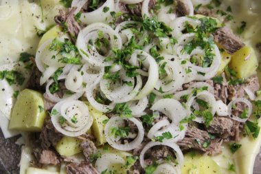 Büyük şeffaf bir tabakta et, tortilla, soğan ve otlarla bezenmiş.