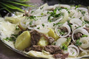 Büyük şeffaf bir tabakta et, tortilla, soğan ve otlarla bezenmiş.