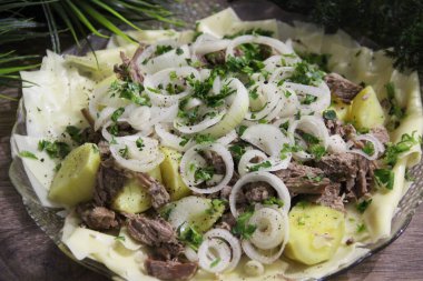 Büyük şeffaf bir tabakta et, tortilla, soğan ve otlarla bezenmiş.