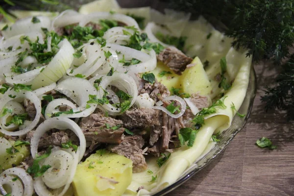 Büyük şeffaf bir tabakta et, tortilla, soğan ve otlarla bezenmiş.