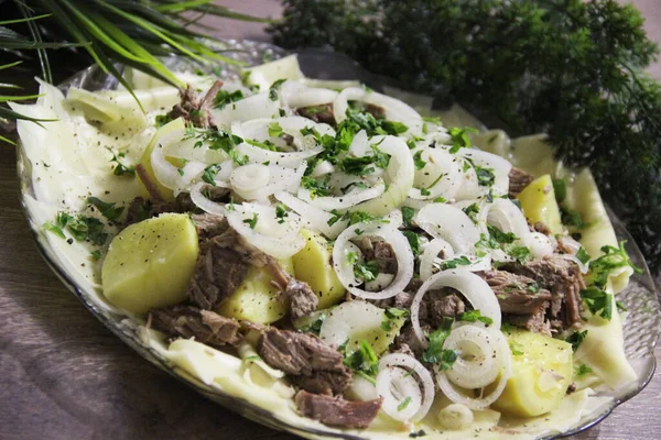 Büyük şeffaf bir tabakta et, tortilla, soğan ve otlarla bezenmiş.