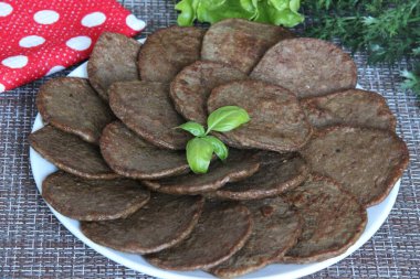 Tabakta ev yapımı tavuk ciğeri krepleri, arkasında kırmızı peçete ve yeşiller.