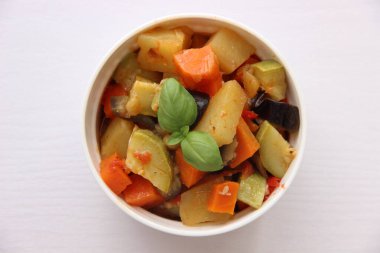 Beyaz arka planda, beyaz bir kupada sebze güveci.