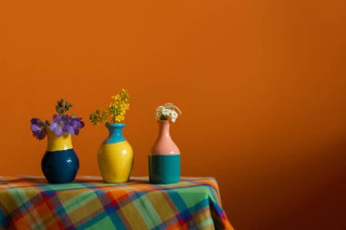 Bahar çiçeklerinin olduğu küçük, şirin vazolar. Sıcak, parlak sarı, turuncu, yeşil renkler, pürüzsüz ışık. Metin için boş fotokopi alanı olan fotoğraf. Kartlar, posterler, web sitesi dekorasyonu için.
