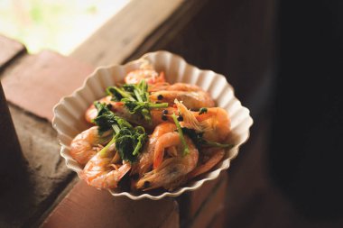 Taze lezzetli ev yapımı deniz ürünleri sıcak turuncu karidesler yeşil otlu karidesler beyaz kasede baharat..