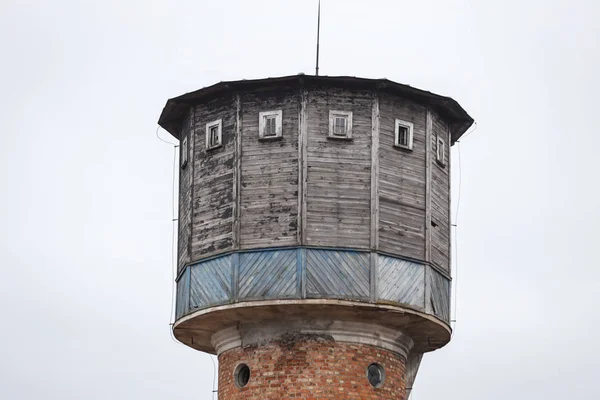 Antigua torre de agua de ladrillo con tapa de madera, situada en un pequeño campo —  Fotos de Stock
