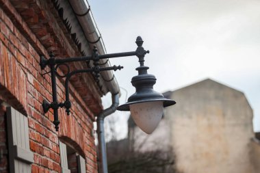 Küçük kirli fener yenilenmiş turuncu tuğlalı fahişeden sarkıyor.