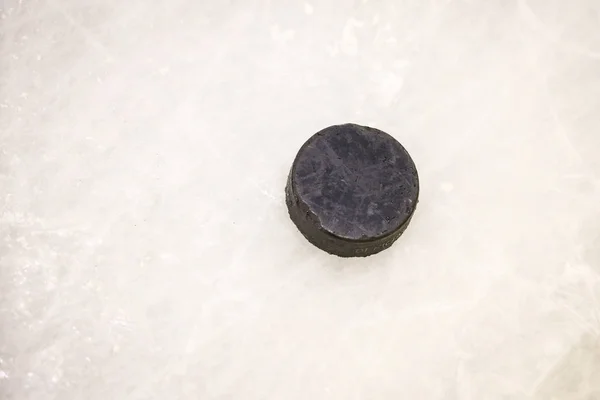 Black ice hocikey rubber puck located on arena ice rink. Ice and — Stock Photo, Image