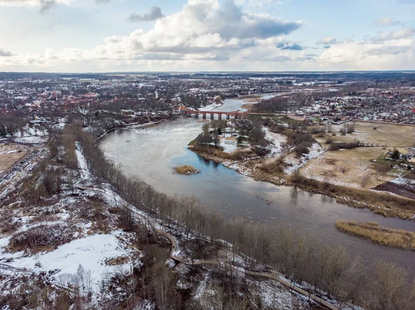Venta nehri ile Kuldiga kırsalının gerçek insansız hava aracı görüntüsü. Fotoğraf, ılık kış gününde karlı bir günde çekildi..