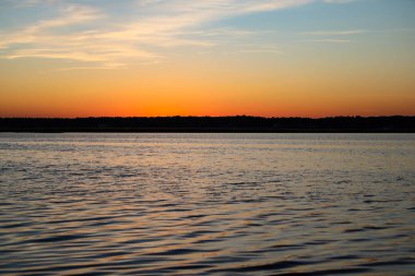 Gün batımında küçük dalgalarla akan nehrin olduğu güzel manzara. Fotoğraf Letonya 'da çekildi, Lielupe..