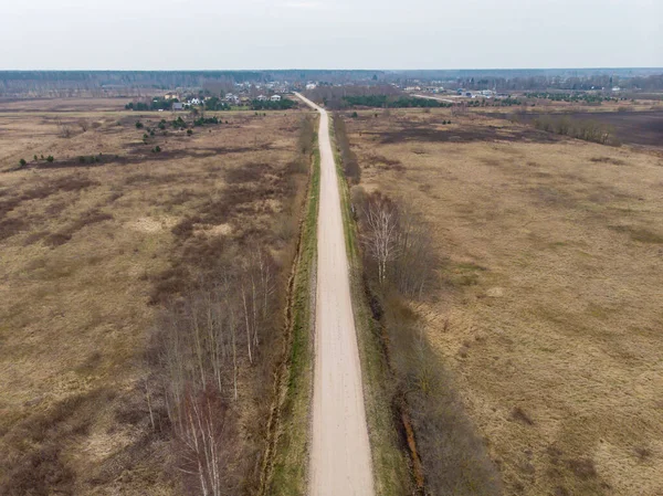 Tarımsal alanların yakınındaki eski kırsal yol manzarası. Fotoğraf Avrupa, Letonya 'da çekildi.