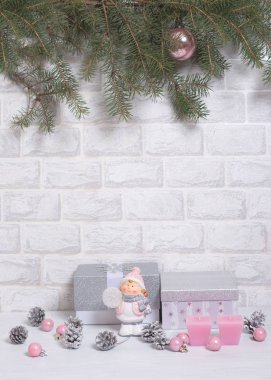 Noel ağacı ve koni, mum ve açık gri arka planda pembe toplu gümüş hediyeler.