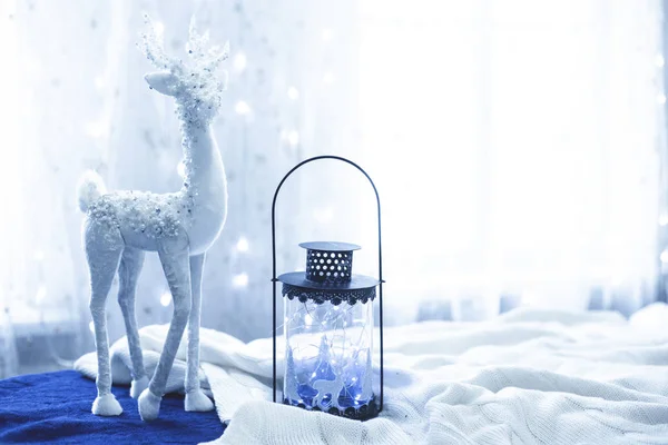 Weihnachtsdekor weißer Hirsch mit dunkler und gläserner Laterne und Lichtern auf blauem und weißem Stoff in der Farbe des Jahres 2020 klassisch blau — Stockfoto