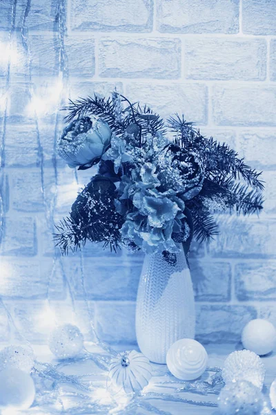 Vánoční výzdoba květin ve váze, bílé koule a světla na bílé cihlové zdi v barvě roku 2020 Classic Blue — Stock fotografie