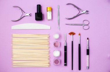 Pembe arka planda manikür ve pedikür ekipmanlarının üst görüntüsü