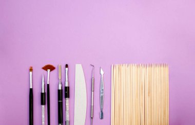 Pembe arka planda manikür ve pedikür ekipmanlarının üst görüntüsü